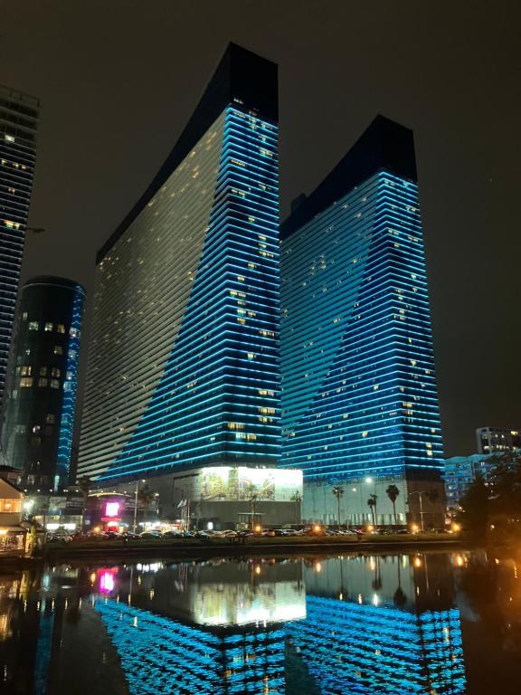 a large building with blue lights on it at night at ORBI CITY Batumi 2 bedrooms Panorama Sea & Mountain View in Batumi