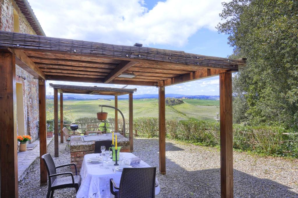 a patio with a table and chairs under a wooden pergola at Appartamenti Villa e Fattoria di Radi Tuscany in Monteroni dʼArbia