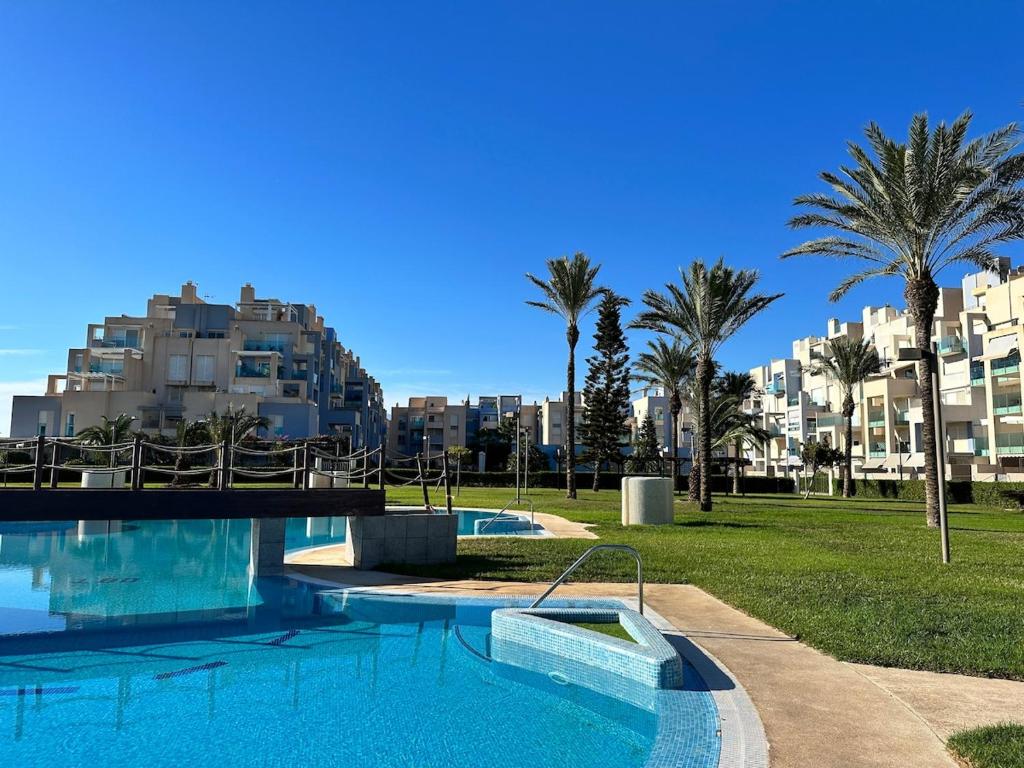 a swimming pool with palm trees and buildings in the background at Playa Serena 2 habitaciones PRIMERA LINEA DE PLAYA Vista al Mar in Roquetas de Mar