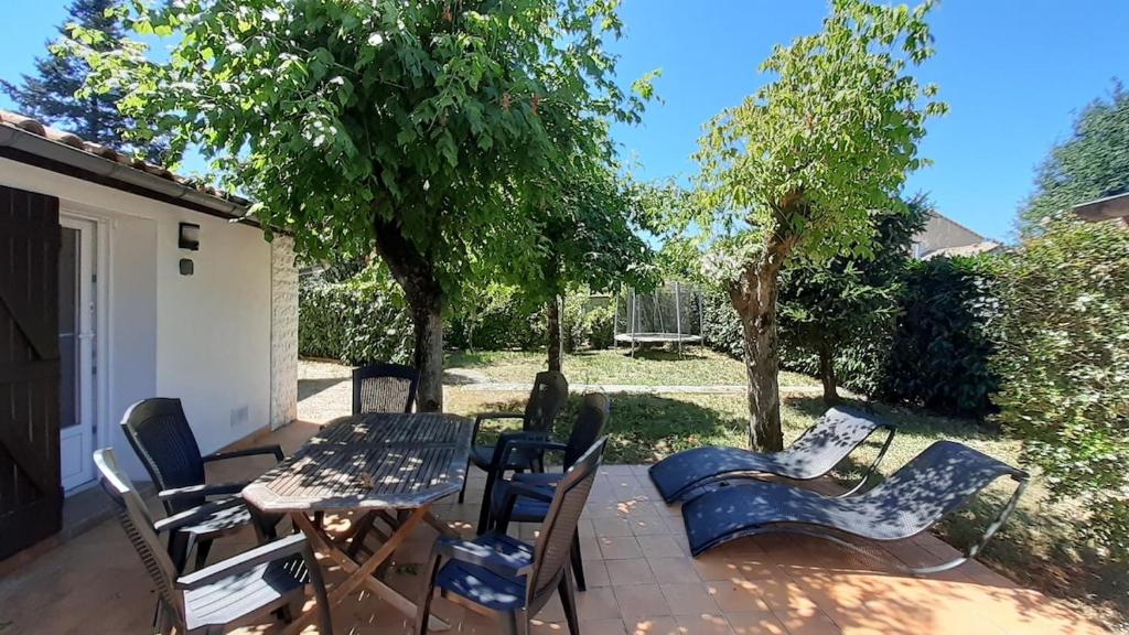 un patio avec une table, des chaises et des arbres dans l'établissement Maison familiale aux carrefours des loisirs, à Le Taillan-Médoc