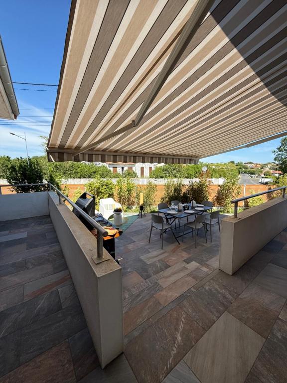 eine Terrasse mit einem Tisch und Stühlen unter einem großen Sonnenschirm in der Unterkunft Villa 45 in Saint-Georges-de-Didonne
