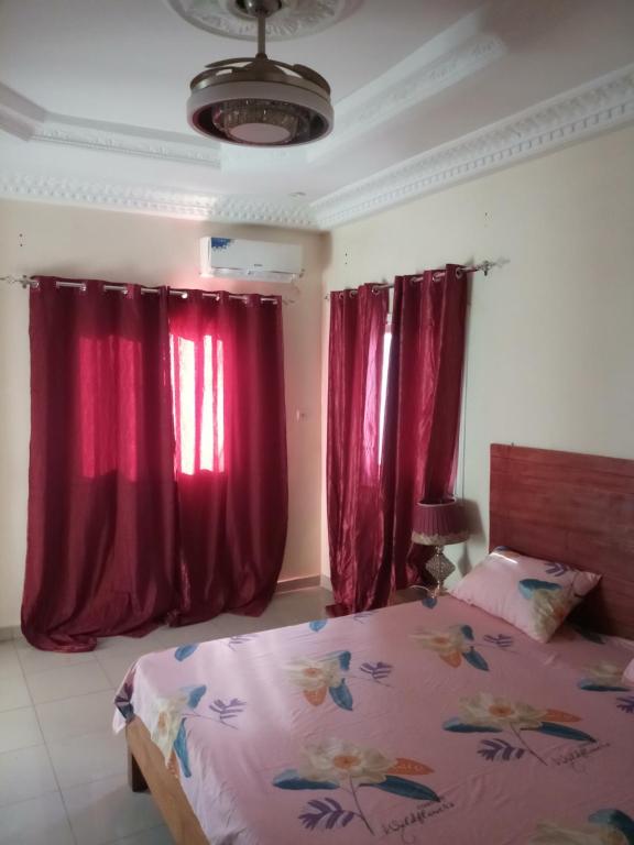 a bedroom with red drapes and a bed with avertisement at S I Appartements in Dakar