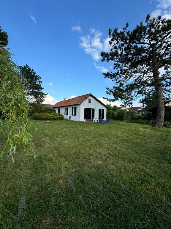 une maison blanche dans un champ avec un arbre dans l'établissement Maison avec Jardin Spacieux proche Touquet, à Cucq