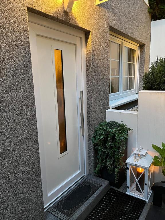 a white front door of a house with a plant at Lovely Souterrain Apartment in Solingen