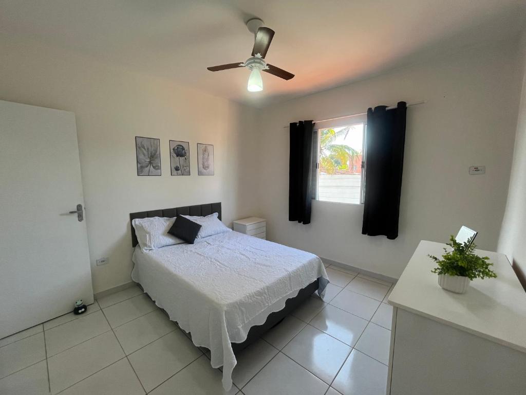 a bedroom with a bed and a ceiling fan at Casa 1 km da Praia Enseada com Garagem in Guarujá