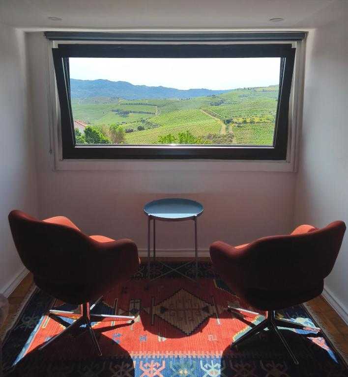 two chairs and a table in a room with a window at BABhouse Casa das Abelhas - Coração do Douro in São João da Pesqueira