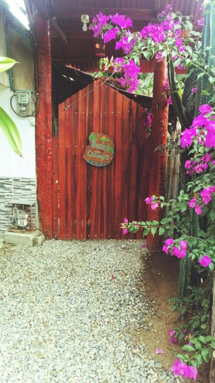 una recinzione rossa con fiori viola e un cartello sopra di Hostel Cattleya a Palomino