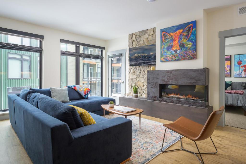 een woonkamer met een blauwe bank en een open haard bij Timber Fox located downtown Winter Park 1307 in Winter Park