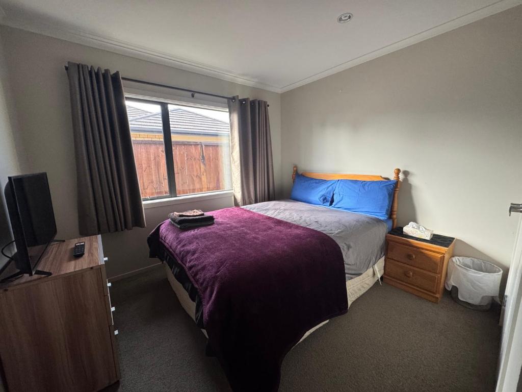 Un pequeño dormitorio con una cama y un televisor. en Home Stay Queen Bed Room 1, en Hamilton