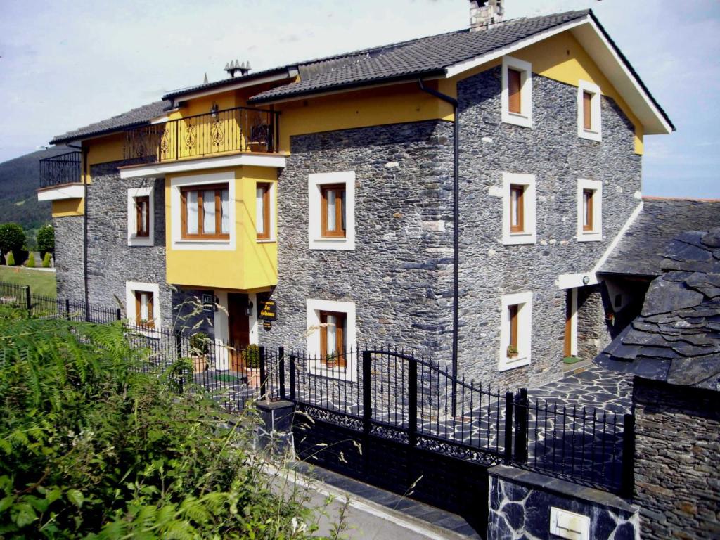 una casa in pietra con una recinzione di fronte di Apartamentos Rurales Los Galpones a Coaña