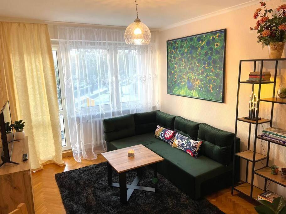 a living room with a green couch and a table at Apartament Pod Pawiem in Olsztyn