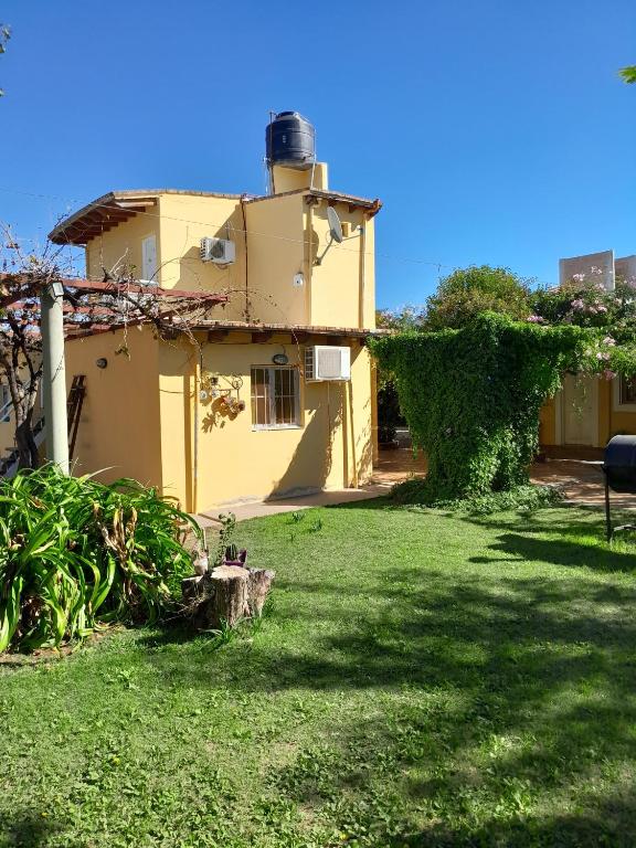 a yellow house with a grassy yard in front of it at Hotel Rincon Serrano in San Agustín de Valle Fértil