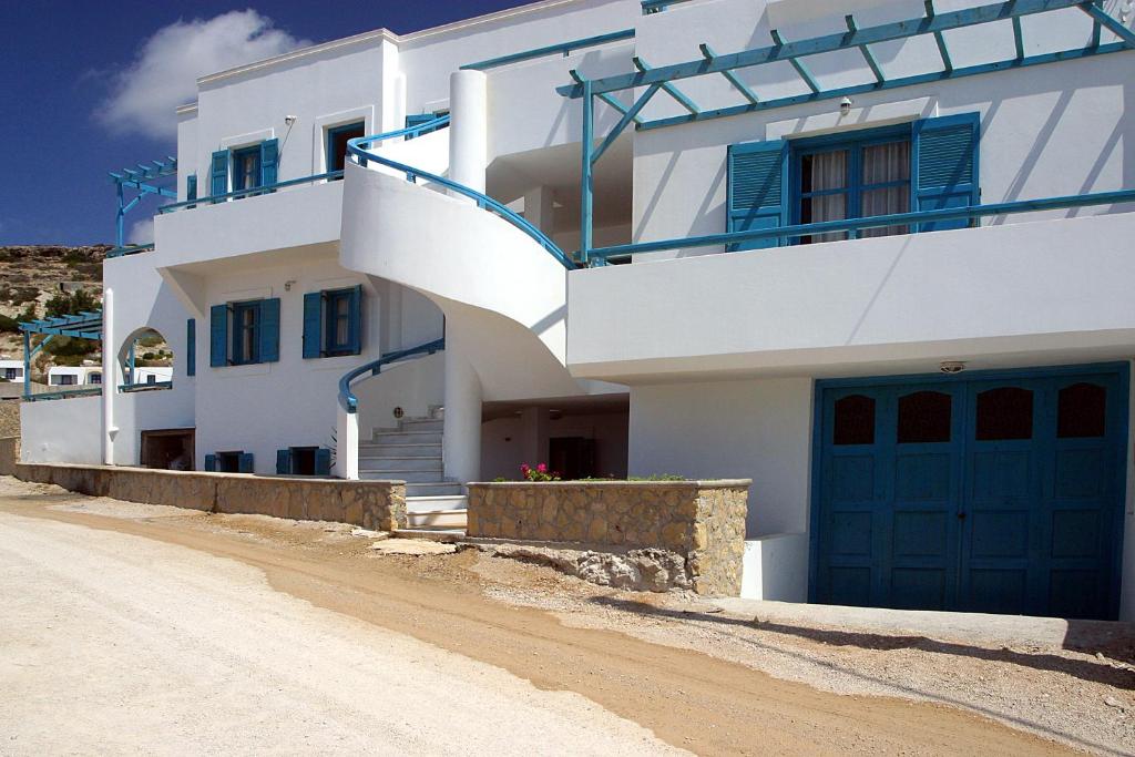 una casa blanca con puertas azules y un camino de tierra en Nefeli Apartments en Lefkos Karpathou