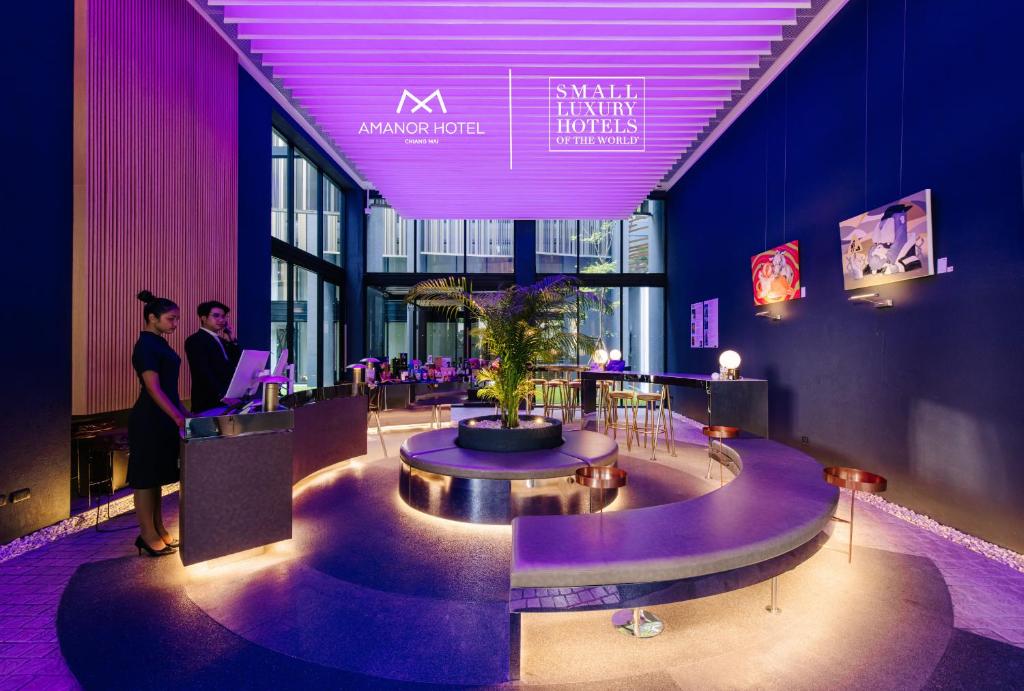 A dramatically lit hotel lobby with a reception desk and central seating area.