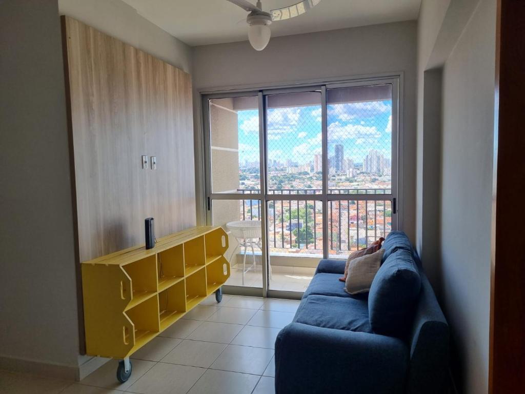 un soggiorno con un divano blu e una grande finestra di Apto versátio trabalho e lazer a Cuiabá