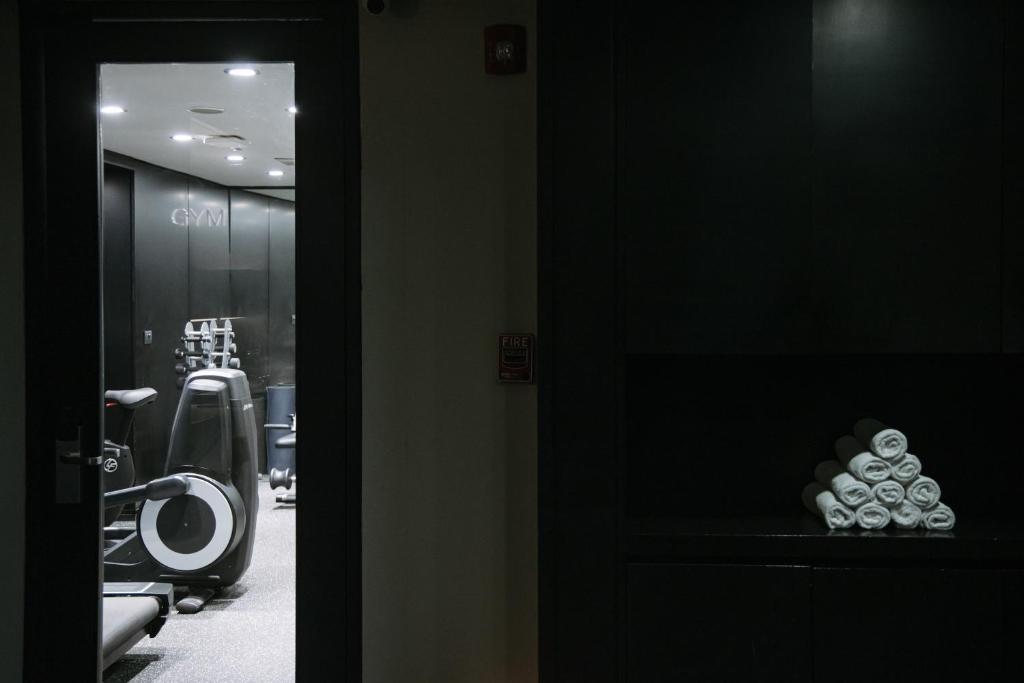 A dark corridor view toward gym equipment, with rolled towels displayed in a niche.