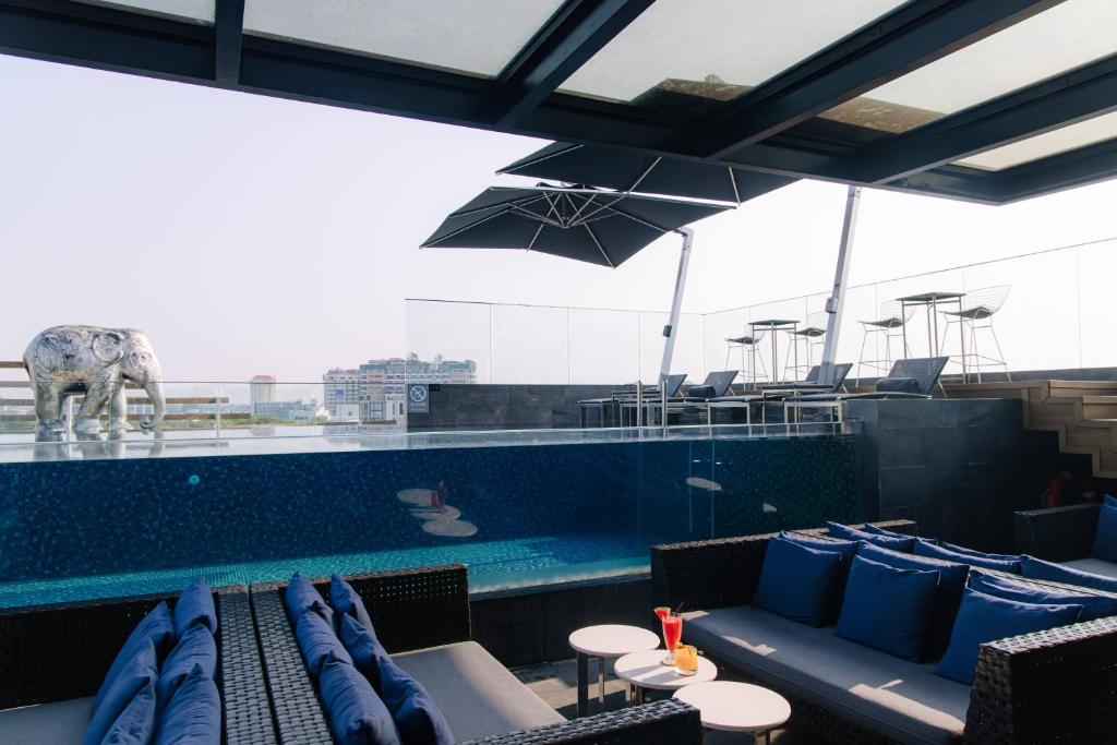 A rooftop pool beside shaded lounge seating and city views.