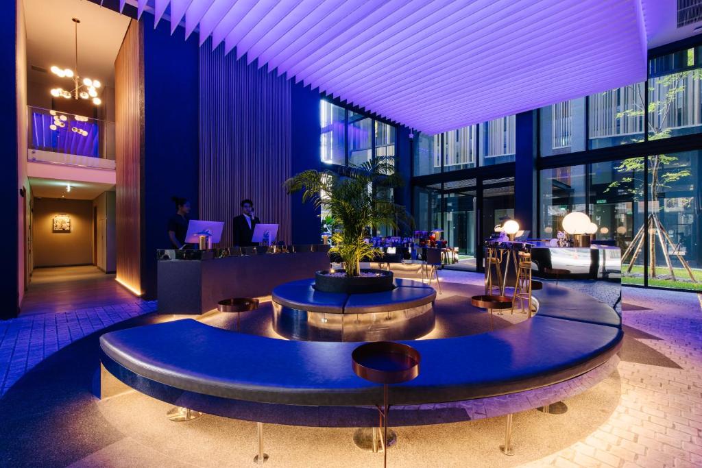 A colorful lobby features a large circular upholstered seating island around a planter.