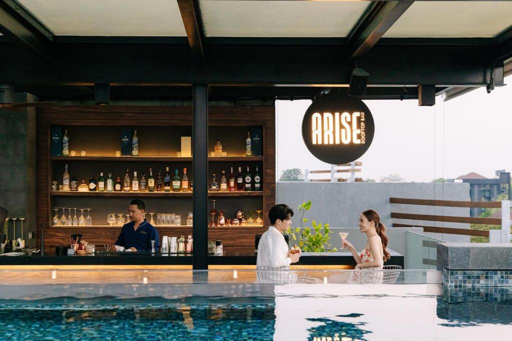 Guests sit at a rooftop pool bar beside the water.