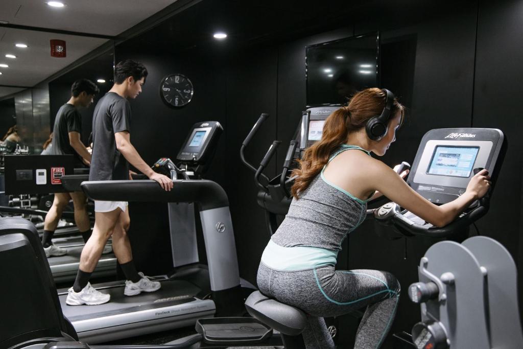 A compact, dark-toned fitness room equipped with treadmills and cardio machines.