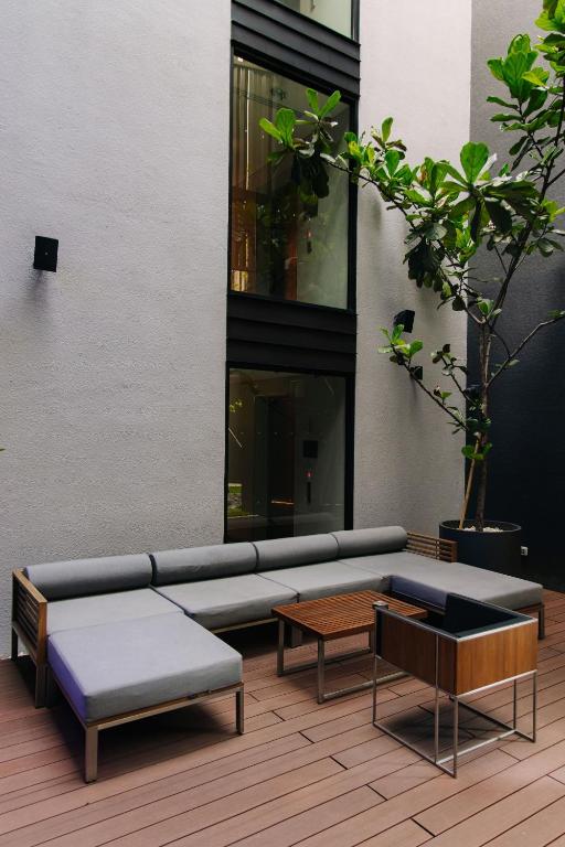 An outdoor courtyard lounge with sectional seating beside a tall window.