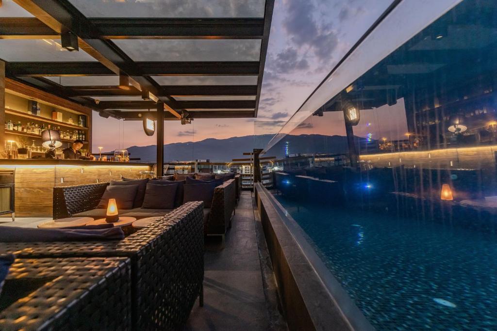 A rooftop pool runs alongside a covered restaurant and lounge at sunset.