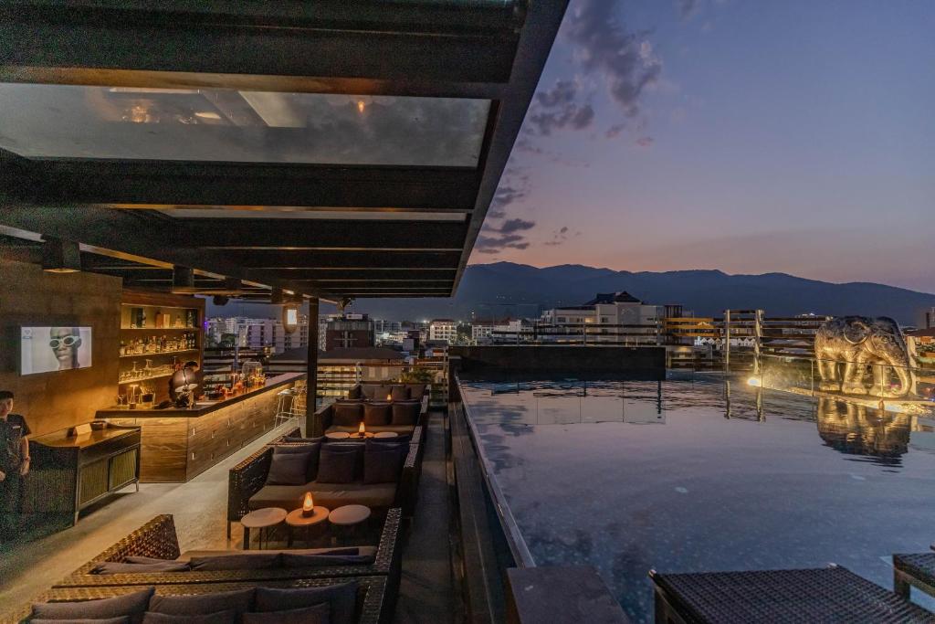 A rooftop pool and lounge overlook Chiang Mai and the mountains at dusk.