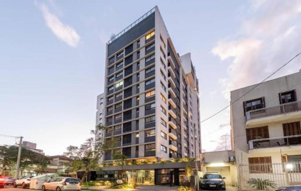 een hoog gebouw met auto's geparkeerd op een parkeerplaats bij Apartamento, Studio, Loft - GO Rio Branco, próximo HCPA e HPS in Porto Alegre
