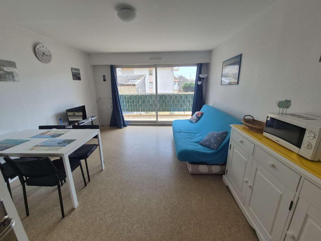 un salon avec une table et un canapé bleu dans l'établissement Appartement proche plage avec parking et wifi - 4 personnes - FR-1-672-38, à Merlimont