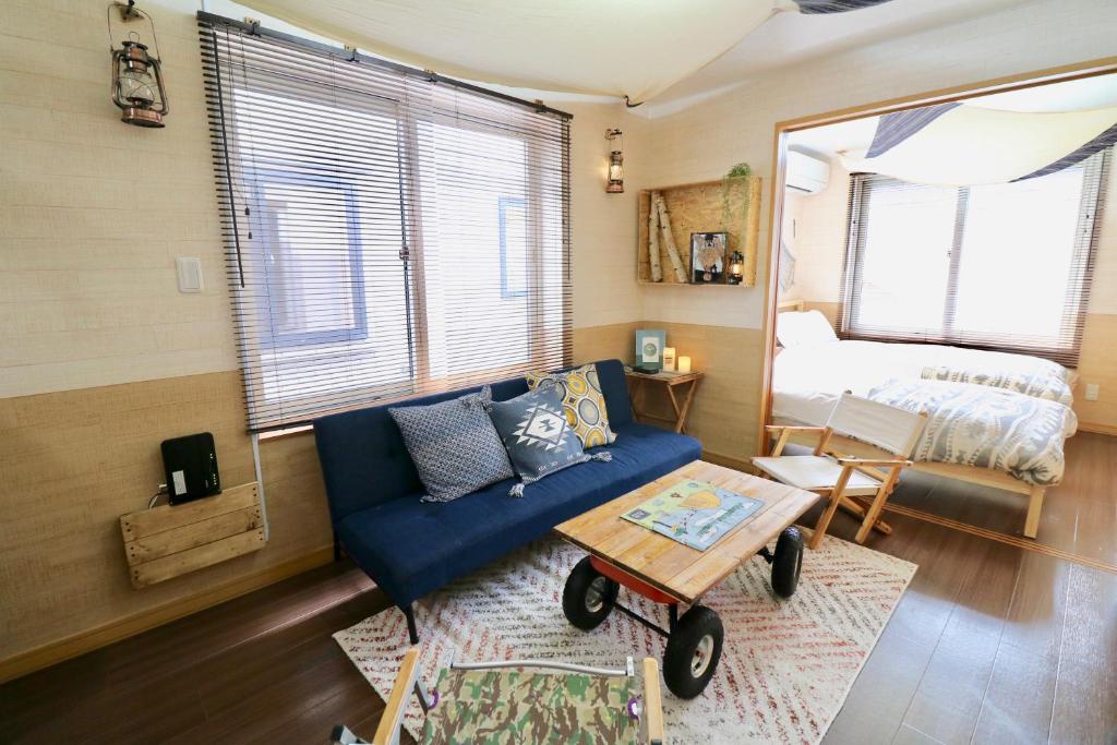 a living room with a blue couch and a bed at Jeunesse Court in Toyohira