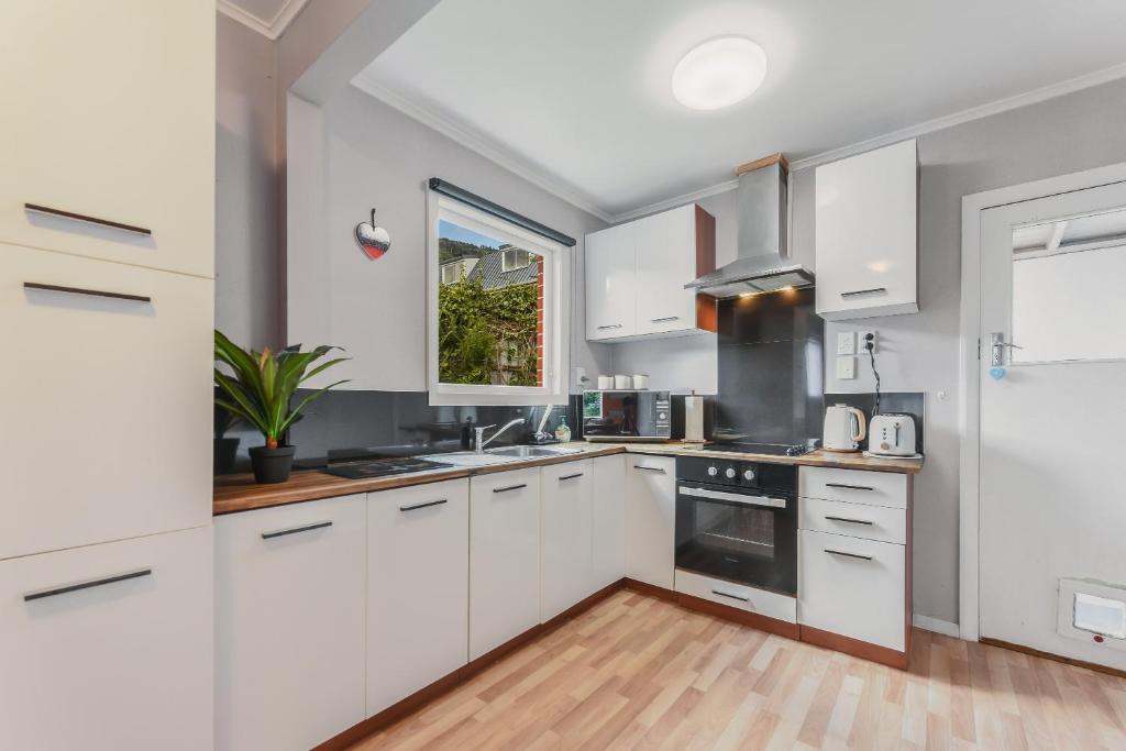 a white kitchen with white cabinets and a window at Picton Central - Picton Holiday Home in Picton