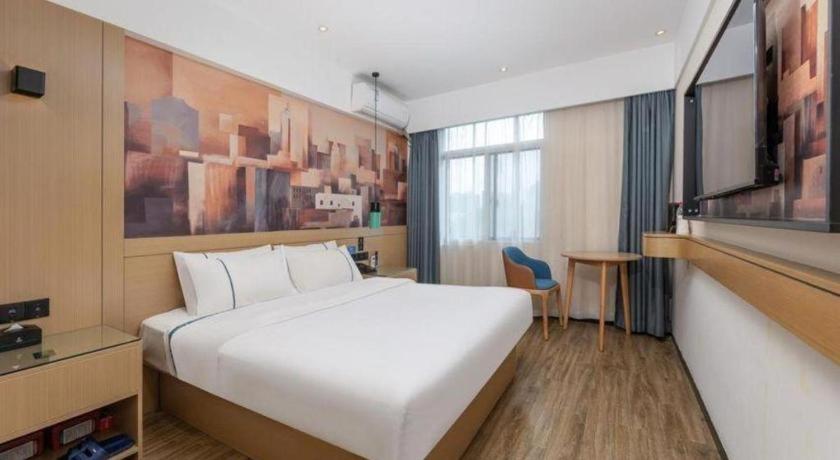 une chambre d'hôtel avec un grand lit blanc et un bureau dans l'établissement City Comfort Inn Kunshan Development Zone Penglang Xinxing Middle Road, à Penglang