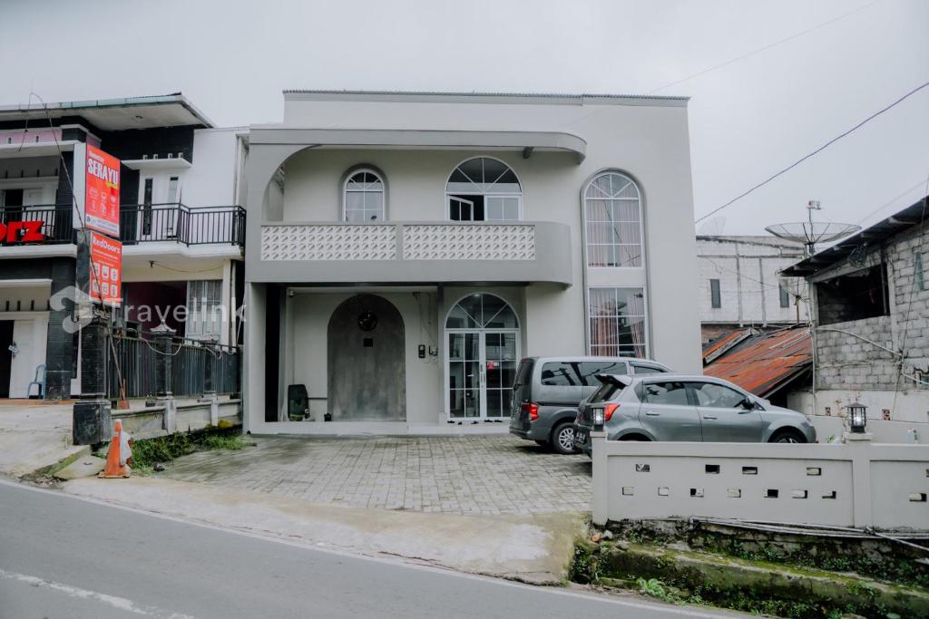 Un edificio blanco con coches aparcados en un estacionamiento. en Dieng Top Syariah By Travelink, en Diyeng