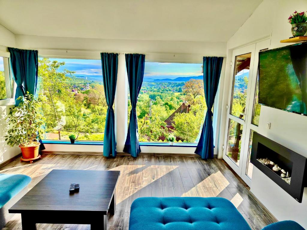 a living room with a blue couch and a large window at Casa De Sub Padure in Bran