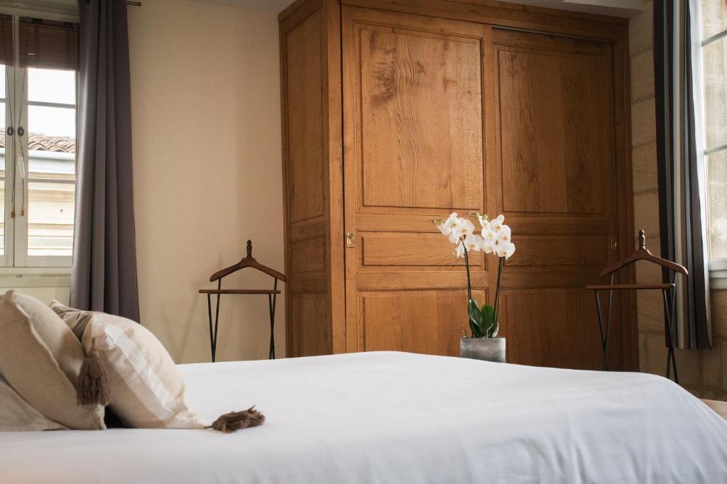 um quarto com uma cama branca e um armário de madeira em Demeure des Girondins em Saint-Émilion