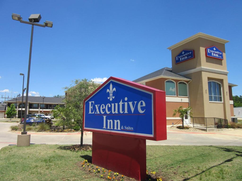 a sign for an executive inn in front of a building at Executive Inn and Suites Tyler in Tyler