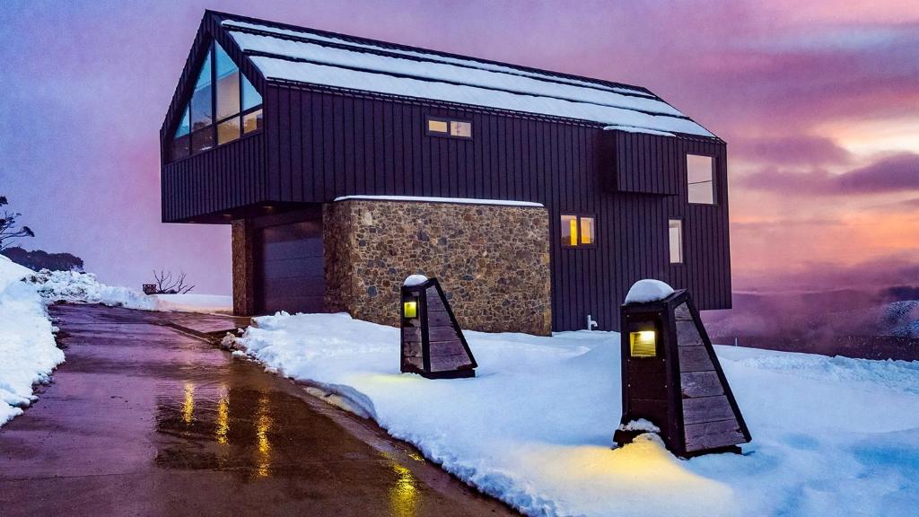 a house in the snow with two lights in it at Peak Chalet in Mount Hotham