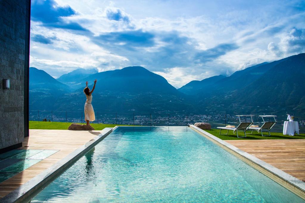 a woman is standing on the edge of a swimming pool at Romantik Chalet im Weingut Eichenstein in Merano