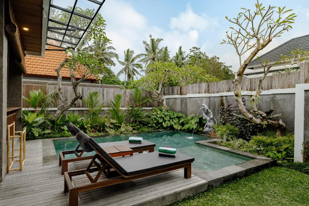 a backyard with a pool with a table and a chair at Badawa Ubud Villa in Ubud