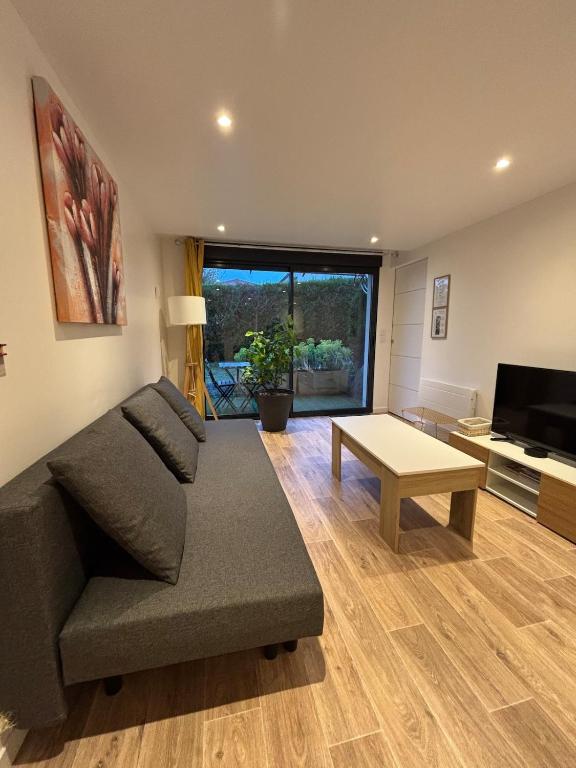 a living room with a couch and a table at Appartement chez maison hôte rez de jardin in Charmeil
