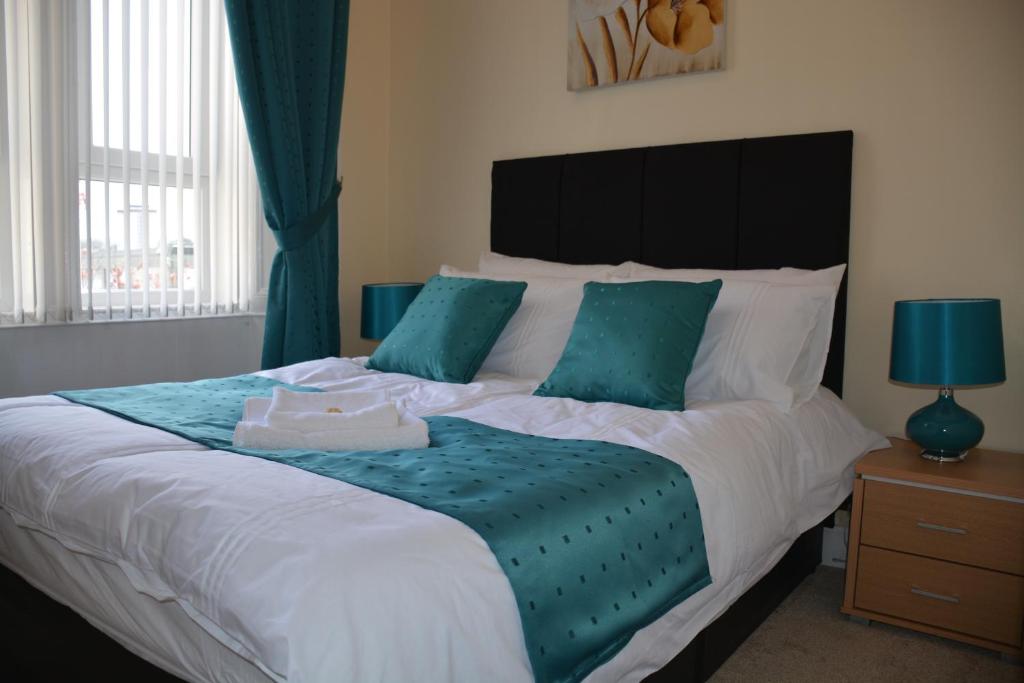 a bedroom with a large bed with blue pillows at Townhead Apartments Gallery View in Paisley