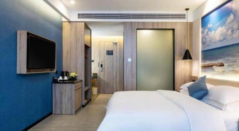a bedroom with a large white bed and a flat screen tv at hailihotel in Dongguan