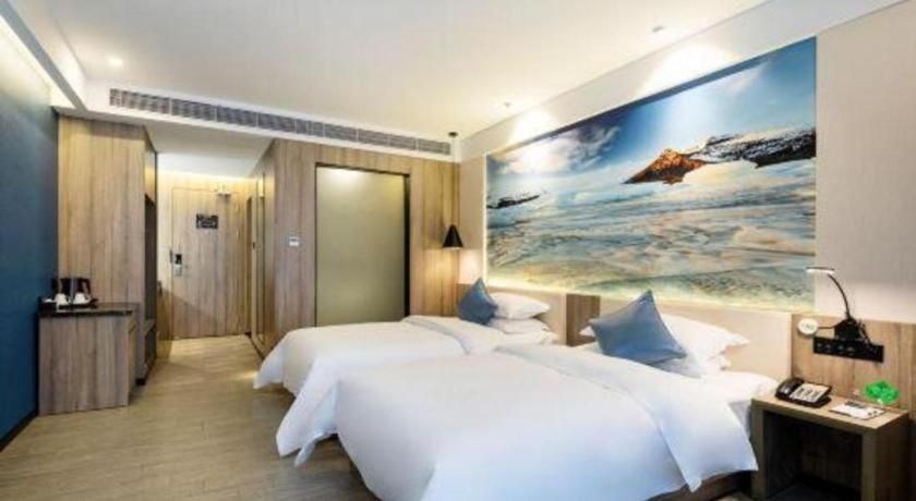 a bedroom with two beds and a painting on the wall at hailihotel in Dongguan