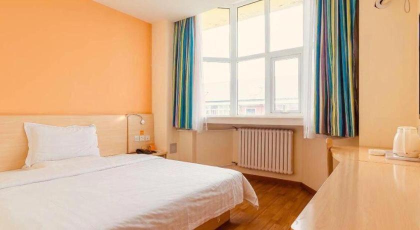 a bedroom with a white bed and a window at 7Days Inn Tianjin Fifth Avenue Youyi Road Branch in Tianjin