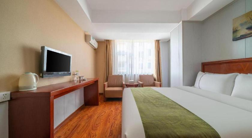 a hotel room with a bed and a flat screen tv at GreenTree Inn Yantai Xingfu Road Marina Plaza Express Hotel in Yantai