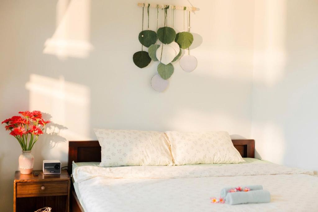 ein Schlafzimmer mit einem weißen Bett und einer Vase aus Blumen in der Unterkunft Green home, Huế in Thôn Trường Giang