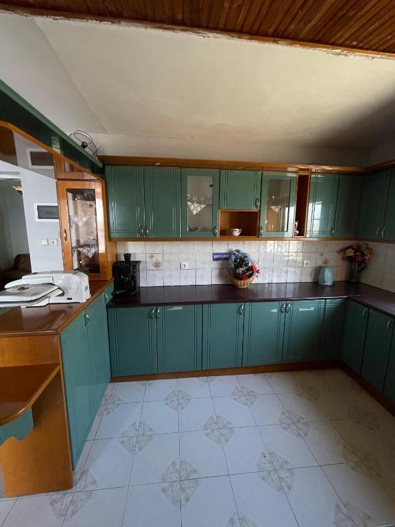 a kitchen with green cabinets and a tile floor at Hotel Gjika in Sarandë