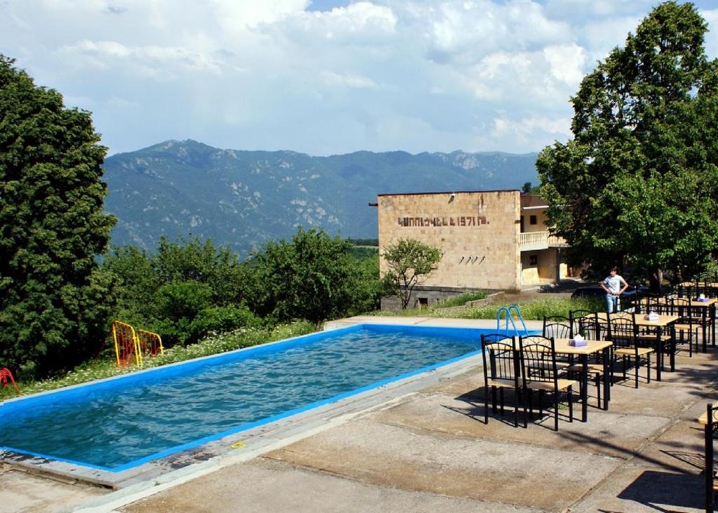 a swimming pool with tables and chairs next to a building at Odzun Hotel in Alaverdi