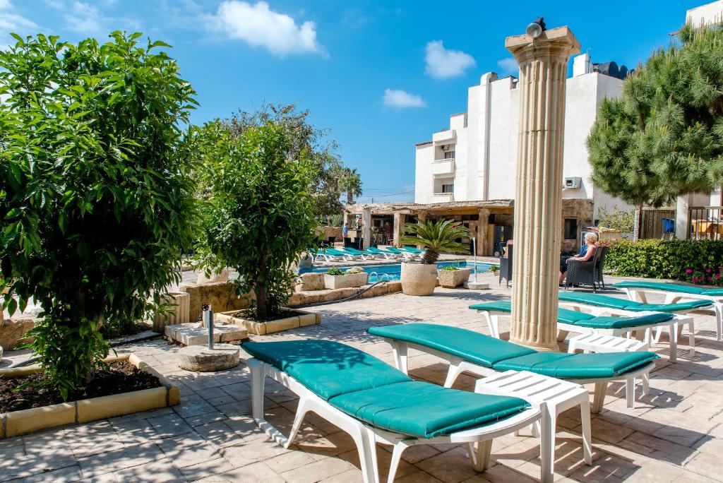a group of lounge chairs and a pool at King's Hotel in Paphos