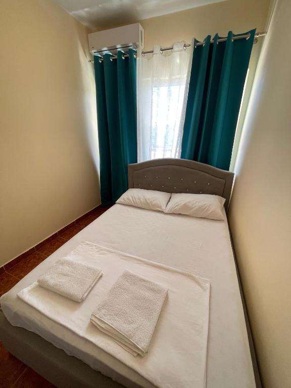 a small bedroom with a bed with blue curtains at Hotel Gjika in Sarandë